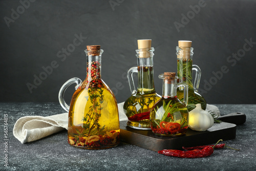 Fototapeta Naklejka Na Ścianę i Meble -  Cooking oil with different spices and herbs in jugs on light grey table