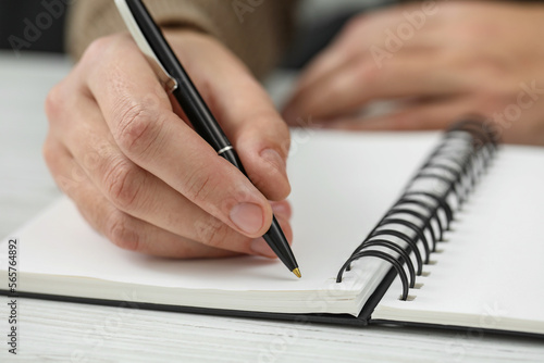 Man writing in notebook at white wooden table, closeup © New Africa