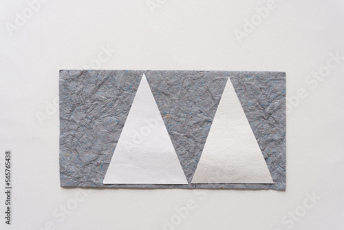 two paper triangles on textured gray paper on a blank surface