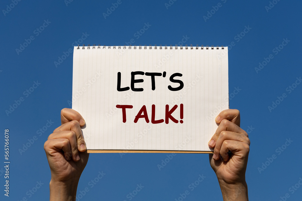 Let's talk text on white paper with blue sky background. This paper is held by 2 hands. This placard can be used for business advertisement to inform team or anyone to start discussion. Let's talk text on white paper with blue sky background. This paper is held by 2 hands. This placard can be used for business advertisement to inform team or anyone to start discussion.