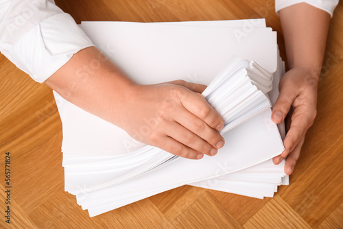 Man stacking documents at wooden table, top view