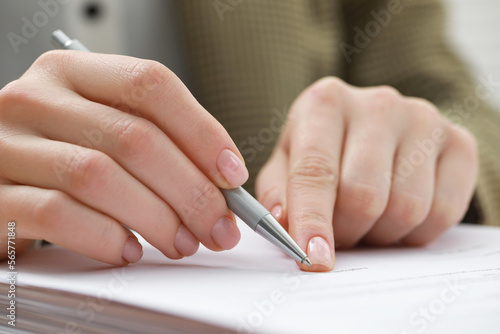 Woman signing documents on workplace, closeup view