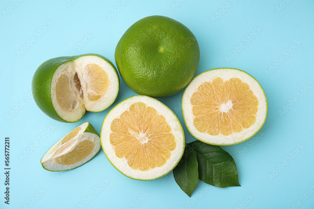Whole and cut sweetie fruits with green leaves on light blue background, flat lay Whole and cut sweetie fruits with green leaves on light blue background, flat lay