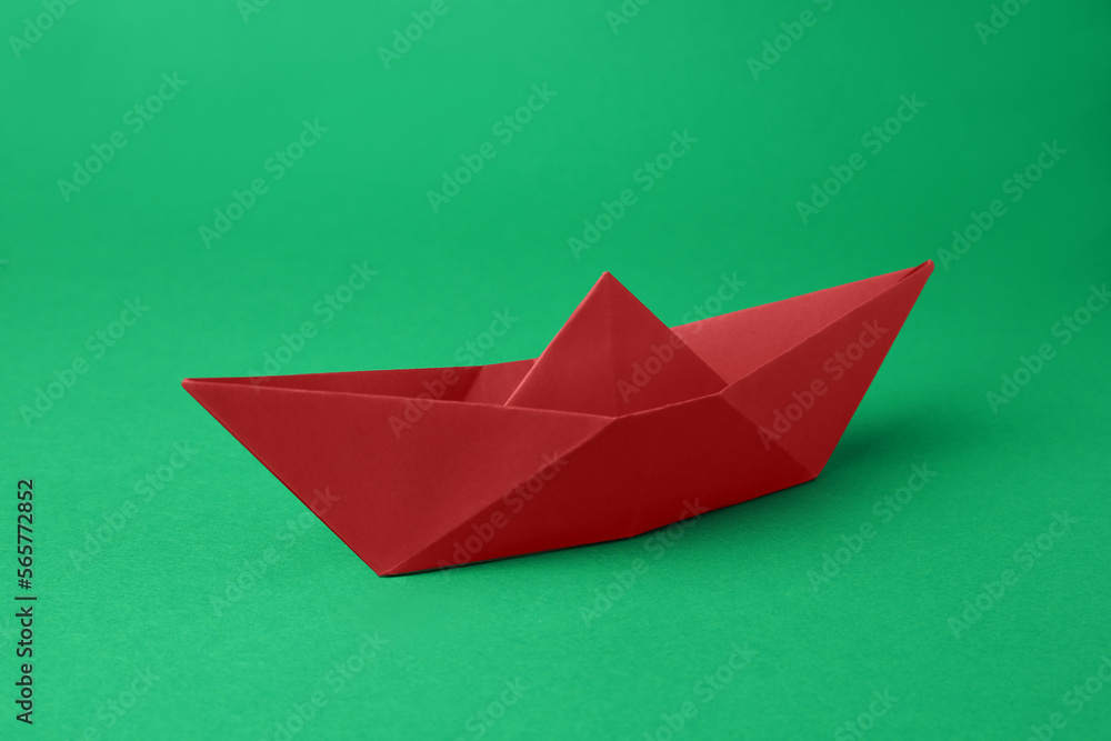 Origami art. Red paper boat on green background Origami art. Red paper boat on green background