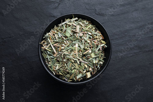 Bowl with aromatic dried lemongrass on black table, top view