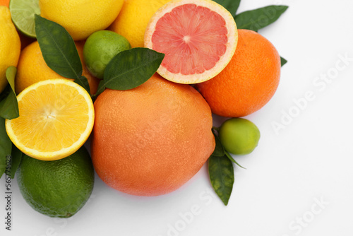 Different citrus fruits and leaves on white background, closeup