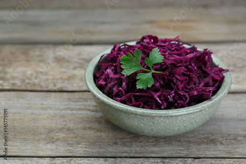 Tasty red cabbage sauerkraut with parsley on wooden table. Space for text