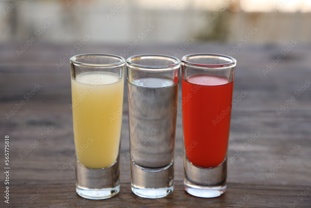 Shots with lime juice, tequila and sangria as colors of mexican flag on wooden table, closeup. Traditional serving Shots with lime juice, tequila and sangria as colors of mexican flag on wooden table, closeup. Traditional serving