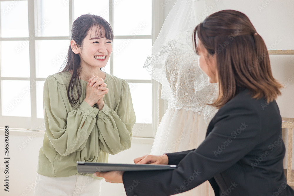ウェディングプランナーとドレス選びの打ち合わせをする女性 ウェディングプランナーとドレス選びの打ち合わせをする女性