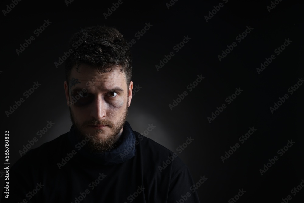 Man with bruise on dark background, space for text. Hostage