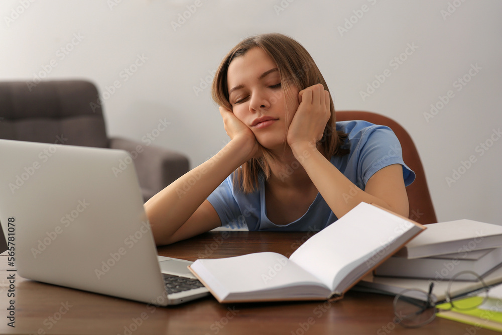 Young tired woman sleeping near books at wooden table indoors Young tired woman sleeping near books at wooden table indoors