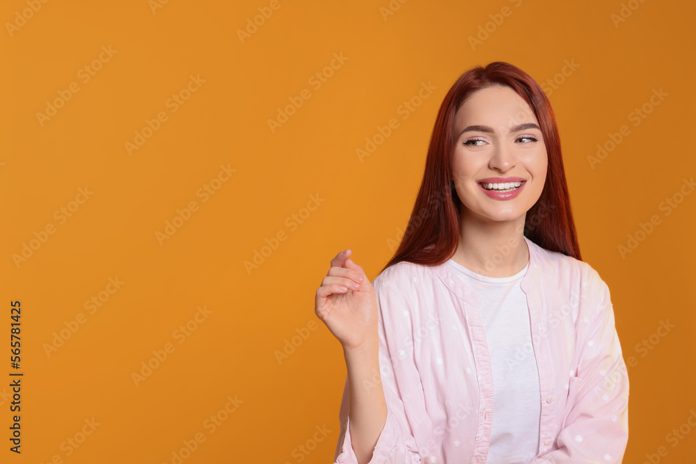 Beautiful woman with red dyed hair on orange background, space for text Beautiful woman with red dyed hair on orange background, space for text