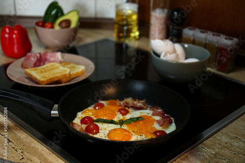 Tasty eggs with tomatoes and bacon in frying pan for breakfast