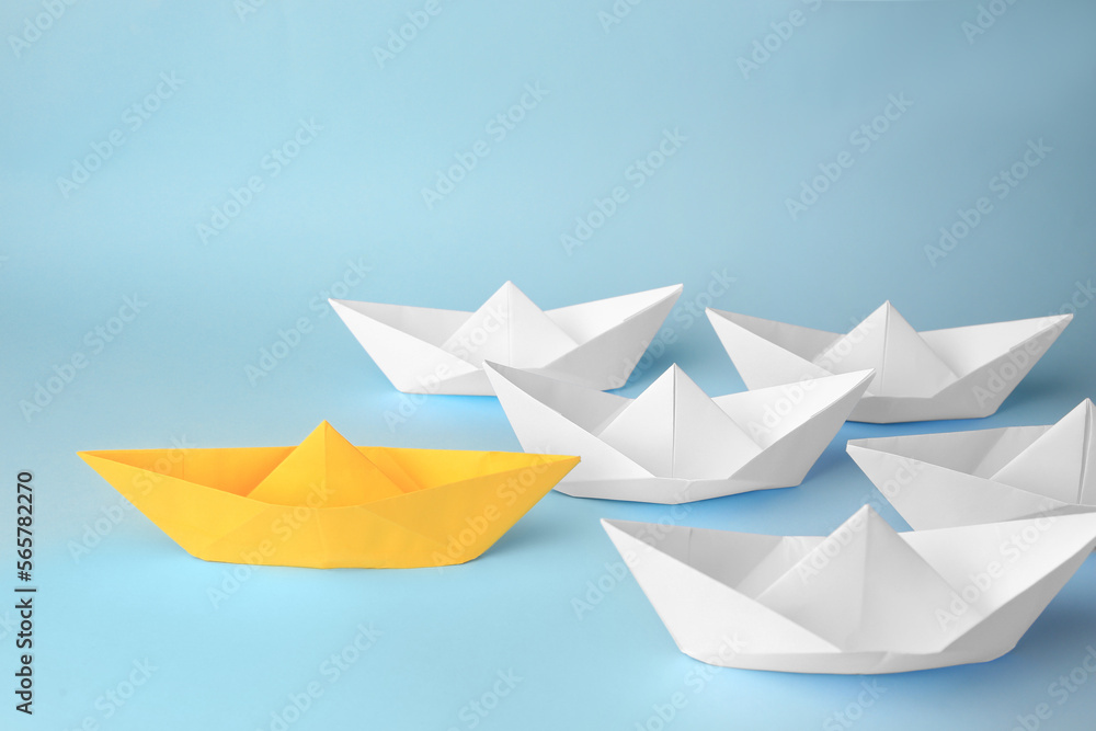 Group of paper boats following yellow one on light blue background. Leadership concept Group of paper boats following yellow one on light blue background. Leadership concept