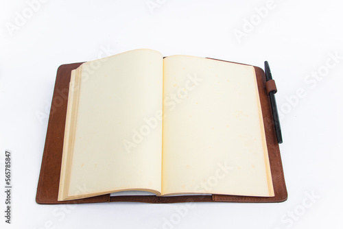 An open hardcover book with blank pages with a pen
