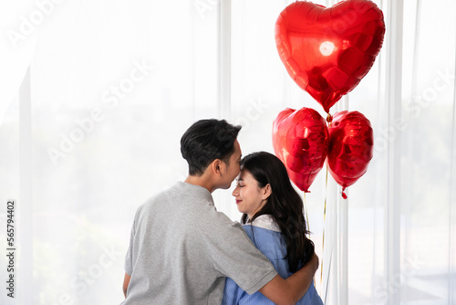  Back view of couple sitting on the bed, couple with red heart shape balloons Valentine's Day  concept.