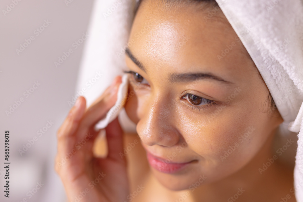 Close up of happy biracial woman wearing towel cleansing face in bathroom Close up of happy biracial woman wearing towel cleansing face in bathroom