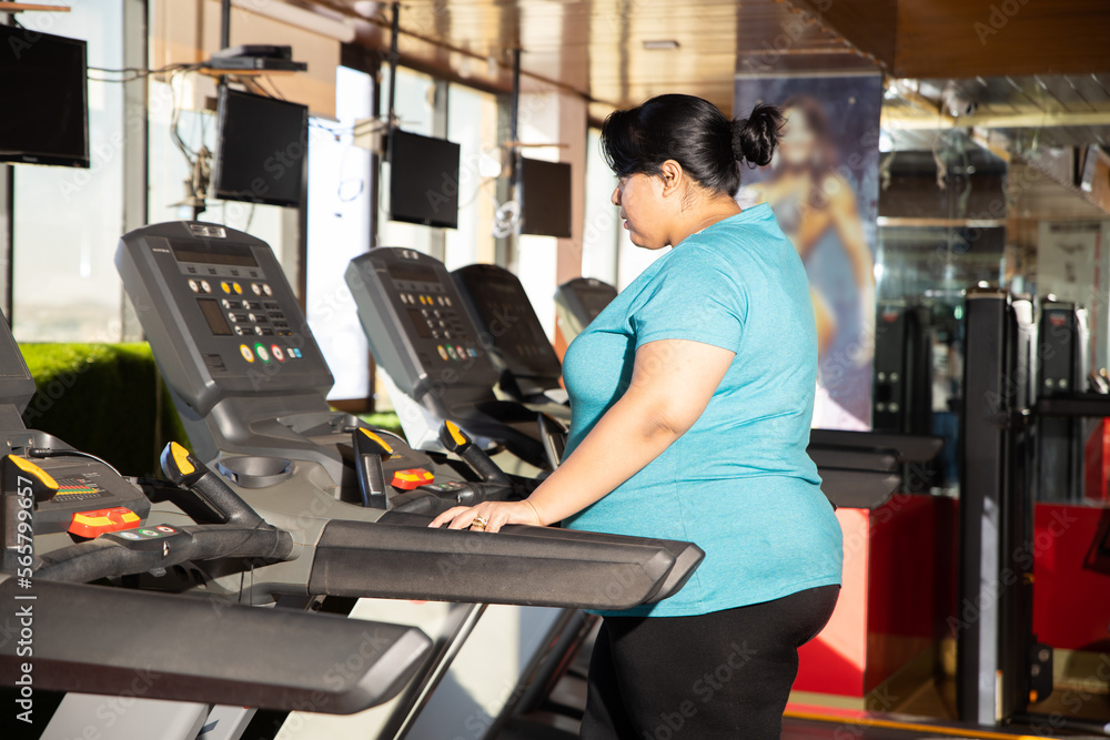 Young overweight indian woman is workout in gym to lose weight. Asian female doing cardio training and running on treadmill. Young overweight indian woman is workout in gym to lose weight. Asian female doing cardio training and running on treadmill.