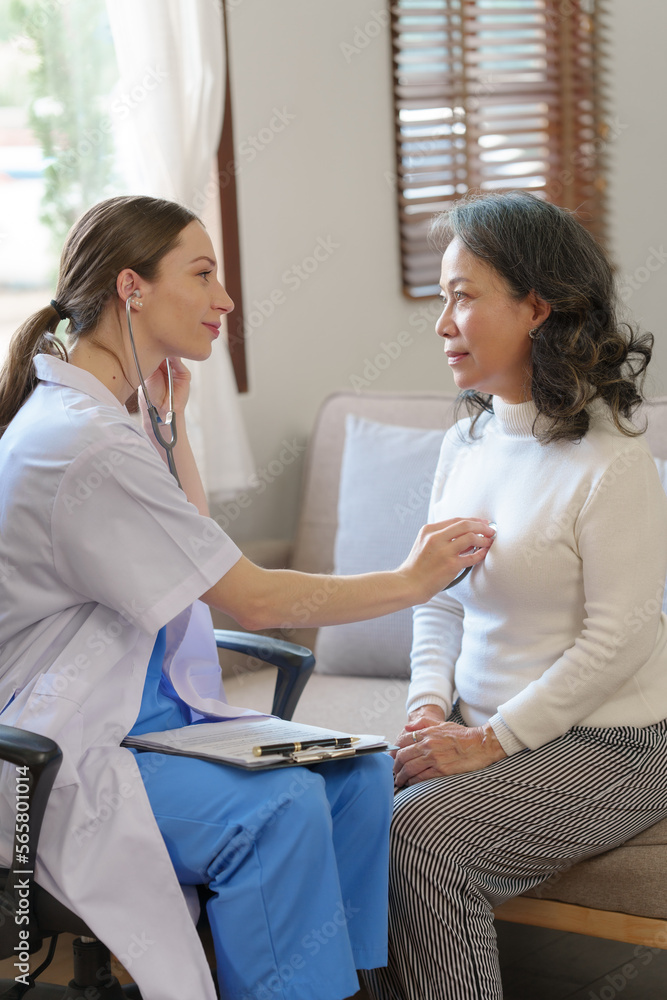 Fototapeta premium Caucasian female nurse using stethoscope to listen heartbeat of elderly patient, young Asian woman to detect abnormal heart rates from insufficient rest