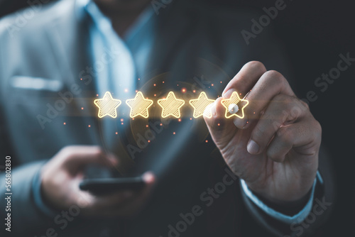 Cuadro en lienzo Businessman writing to review and give glowing golden stars for excellent rating from evaluation survey after use product and service , Customer experience and quality feedback concept