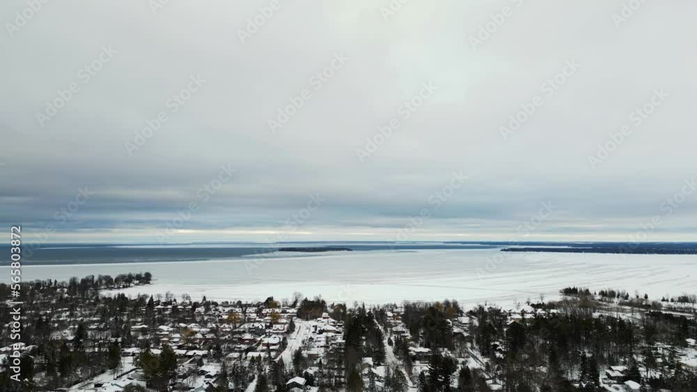 Winter time Lake Simcoe drone view frozen lake houses and treetops cloudy day Winter time Lake Simcoe drone view frozen lake houses and treetops cloudy day