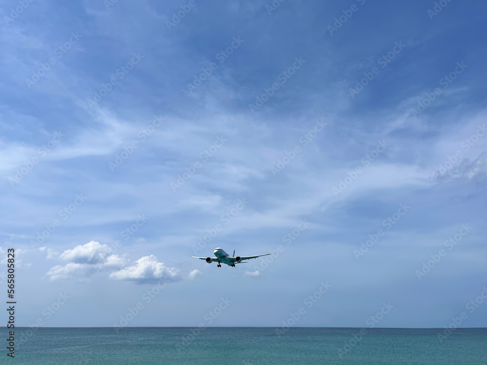 Plane flies low above the sea. Picturesque photo. Blue sky with clouds. Skyline. Passenger, cargo transportation. Boeing 787-8 aircraft model. Aviation. Airplane in flight. Air transport. Panorama. 
