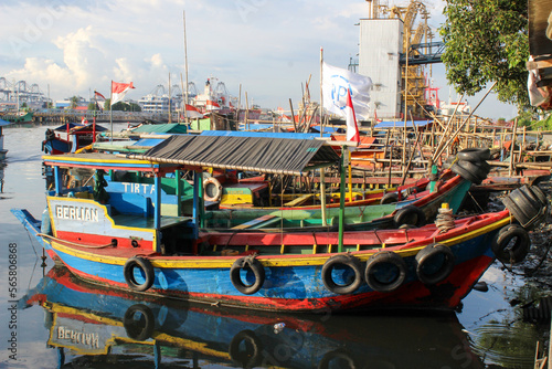 portrait of traditional fishing boats that lean on the dock beside the largest container port in Indonesia