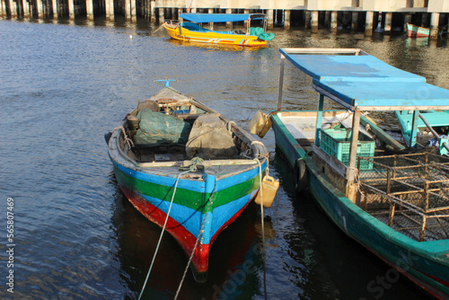 portrait of traditional fishing boats that lean on the dock beside the largest container port in Indonesia © rozi