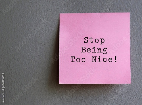 Pink note on wall with text STOP BEING TOO NICE - concept of self reminder to stop trying so hard to be nice , please others to seek acceptance or approval, start setting boundary and speak your mind photo