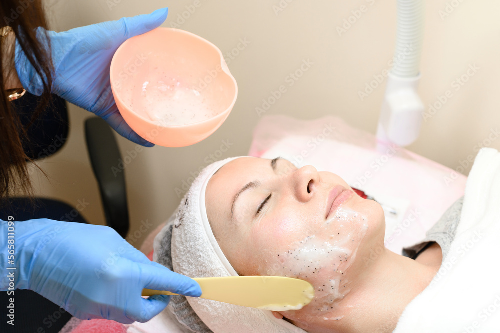 The process of applying a moisturizing mask to the face in a spa salon.