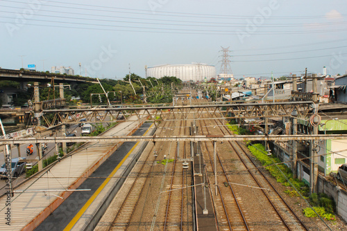 Railroad line near slum housing under high voltage power poles with Jakarta International Stadium behind