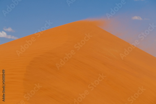 Telephoto shot of Dune 45  Namibia  with distant climbers on top  in a sand storm.