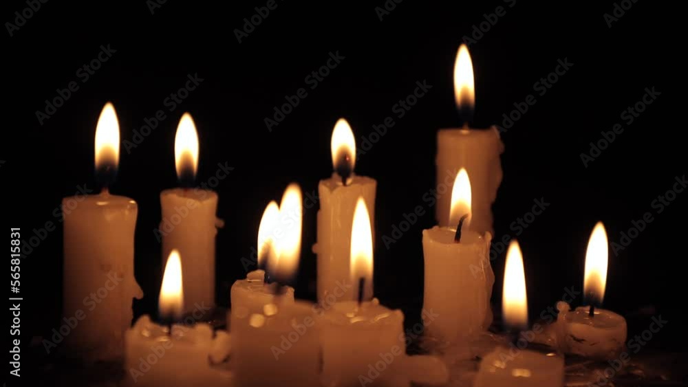 A few candles glow in the dark. Burning candles on a black background. Yellow candles. The flame burns out. Prayer for peace and tranquility. Spirituality and faith A few candles glow in the dark. Burning candles on a black background. Yellow candles. The flame burns out. Prayer for peace and tranquility. Spirituality and faith