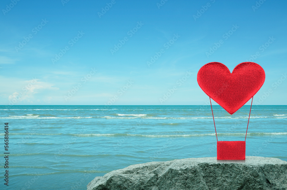 Fototapeta premium Red fabric heart love air balloon on rock mountain over tropical sea and blue sky, Valentines day concept