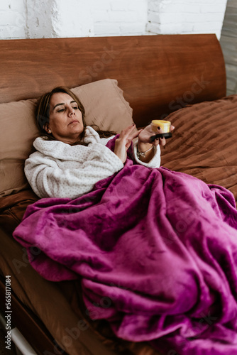 latin adult woman with balsam, ointment or holding jar of cream for flu on bed at home in Mexico Latin America 