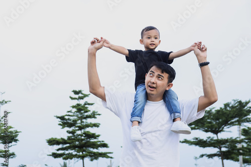 Father and son playing together with rising hands or open arms flying on sky.