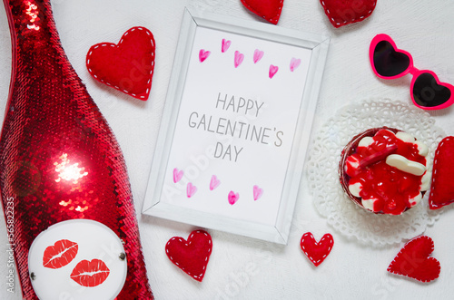 Happy Galentine`s day greeting card. A bottle of vine, a sweet dessert, a red felt hearts with stitches, pink sunglasses and frame with text.	