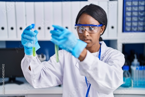 Young african american woman scientist holding test tubes at laboratory