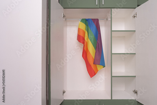 Rainbow flag hangs inside a closet, doors half opened. Fear of coming out concept. Internalized shame with homosexuality metaphor. LGBT guilt symbol. photo