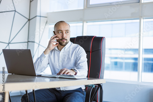 Portrait of a business young successful man in a modern office sitting at a table