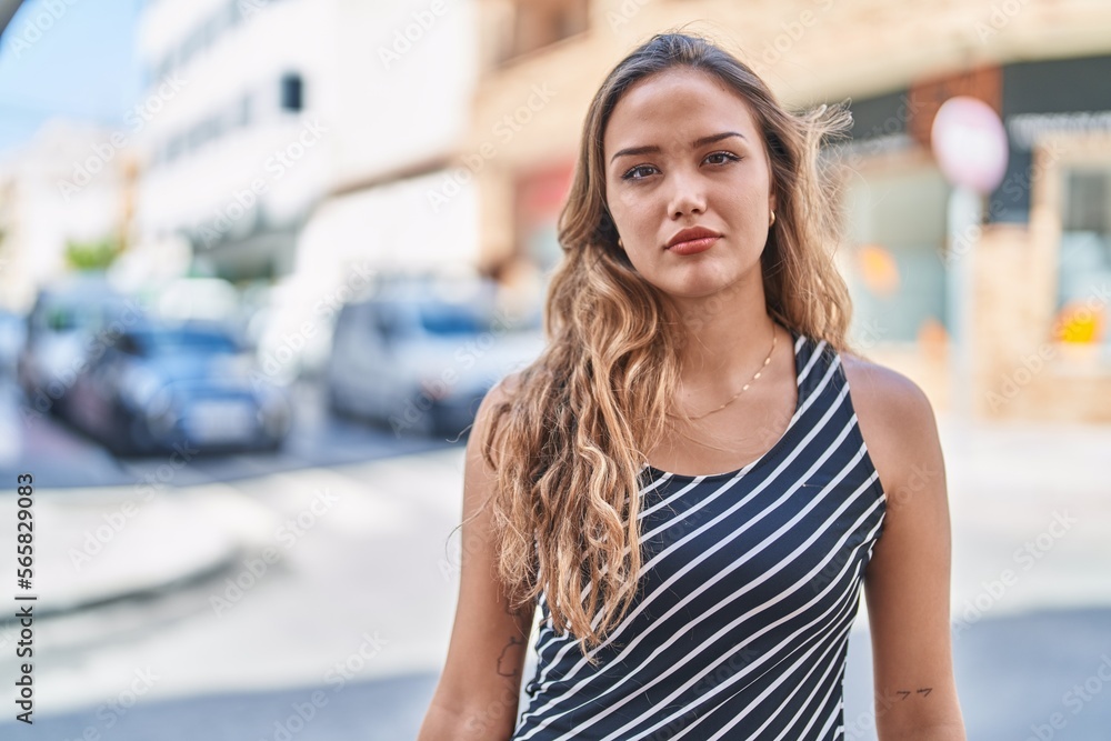 Young beautiful hispanic woman standing with serious expression at street