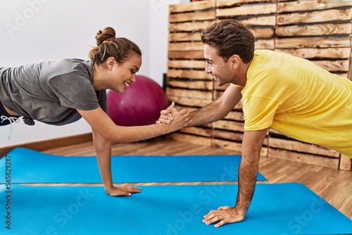 Man and woman couple smiling confident training abs exercise at sport center