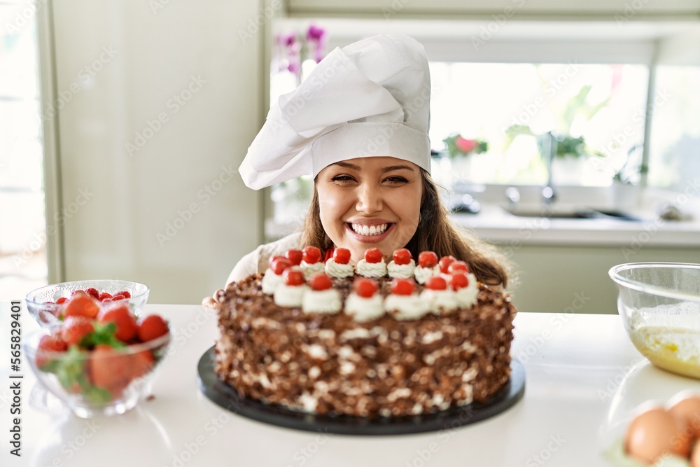 Young beautiful hispanic woman smiling confident smelling cake at the kitchen Young beautiful hispanic woman smiling confident smelling cake at the kitchen