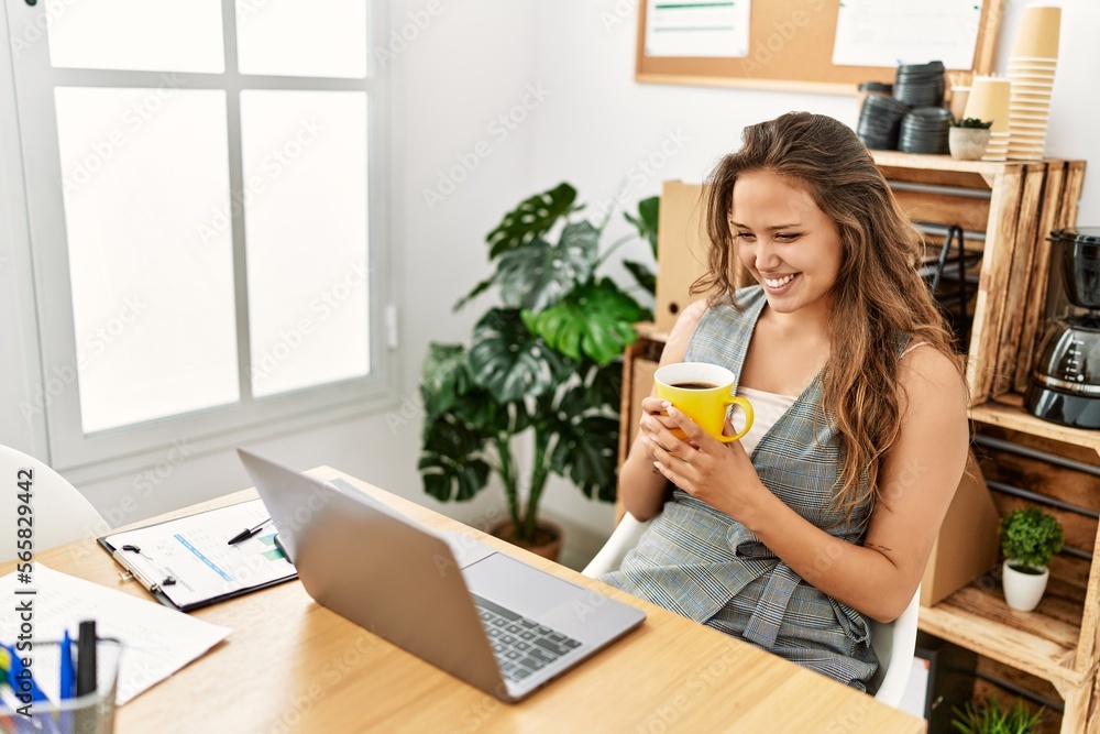 Young beautiful hispanic woman business worker using laptop drinking coffee at office Young beautiful hispanic woman business worker using laptop drinking coffee at office