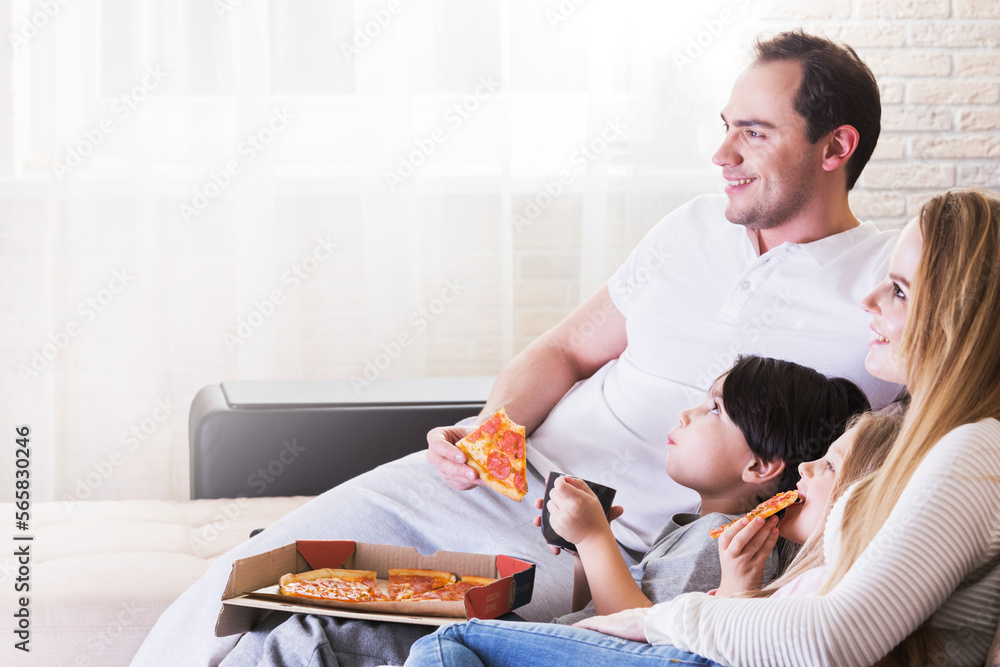 Happy family eating pizza while watching TV Happy family eating pizza while watching TV