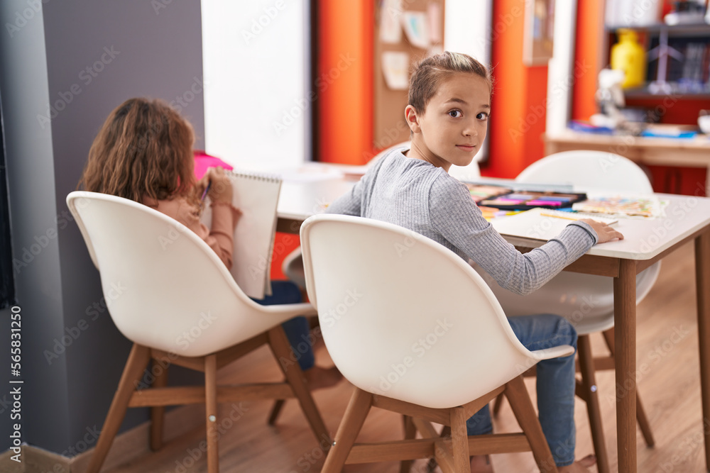 Two kids students sitting on table drawing on notebook paper at classroom Two kids students sitting on table drawing on notebook paper at classroom