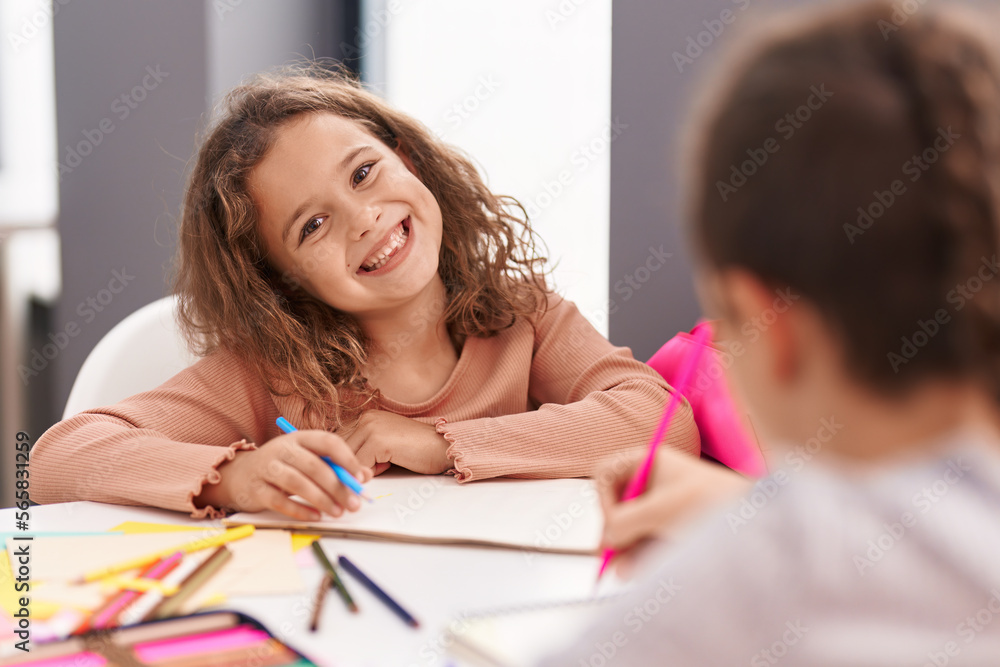 Two kids students sitting on table drawing on notebook paper at classroom Two kids students sitting on table drawing on notebook paper at classroom