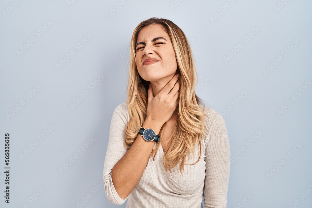 Young blonde woman standing over isolated background touching painful neck, sore throat for flu, clod and infection Young blonde woman standing over isolated background touching painful neck, sore throat for flu, clod and infection
