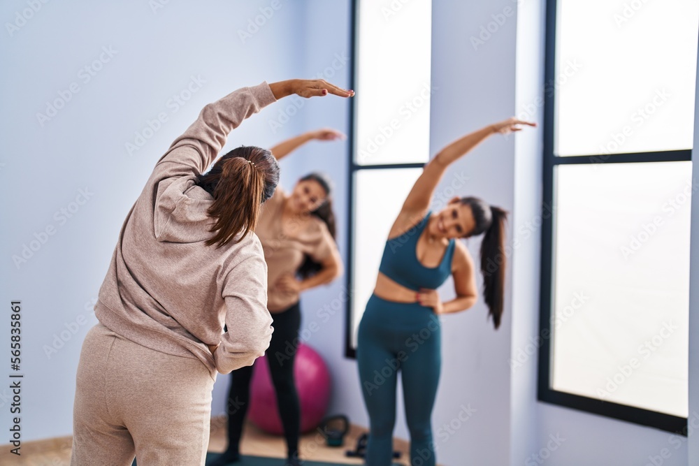 Fototapeta premium Three woman wearing sportswear stretching at sport center