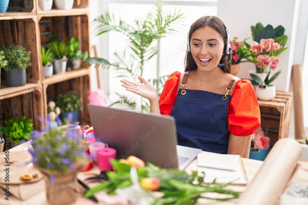 Young hispanic woman working at florist shop doing video call celebrating achievement with happy smile and winner expression with raised hand Young hispanic woman working at florist shop doing video call celebrating achievement with happy smile and winner expression with raised hand